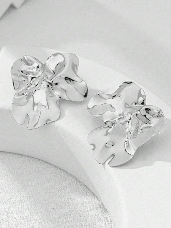 Duże srebrne kolczyki w kształcie nieregularnych, pofalowanych płatków o błyszczącej powierzchni (1).webp
