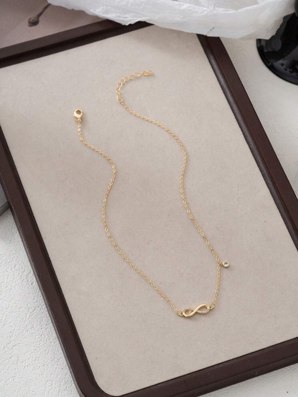 Złoty naszyjnik z symbolem nieskończoności i małą wiszącą zawieszką na cienkim łańcuszku (3).webp