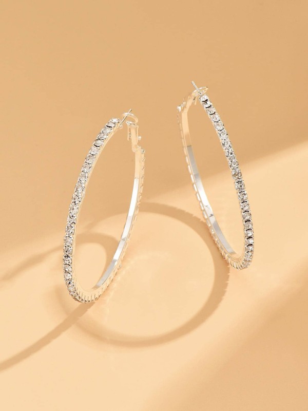 Srebrne kolczyki koła z drobnymi błyszczącymi kamieniami na jasnym tle (1).webp