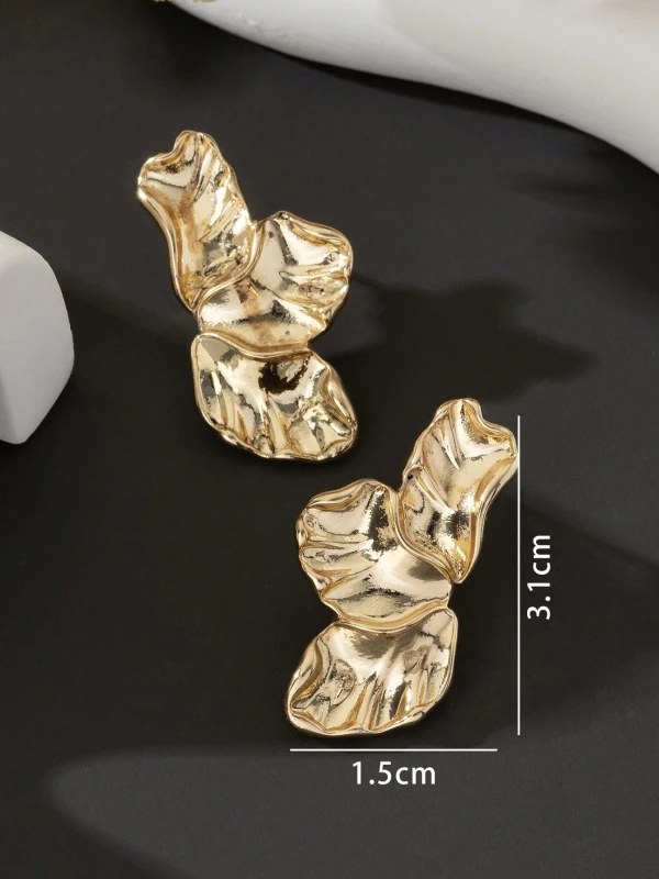Złote kolczyki Golden Petals w formie trzech nieregularnych, rzeźbionych listków lub płatków, pokazane na uchu i na jasnym tle (1).webp