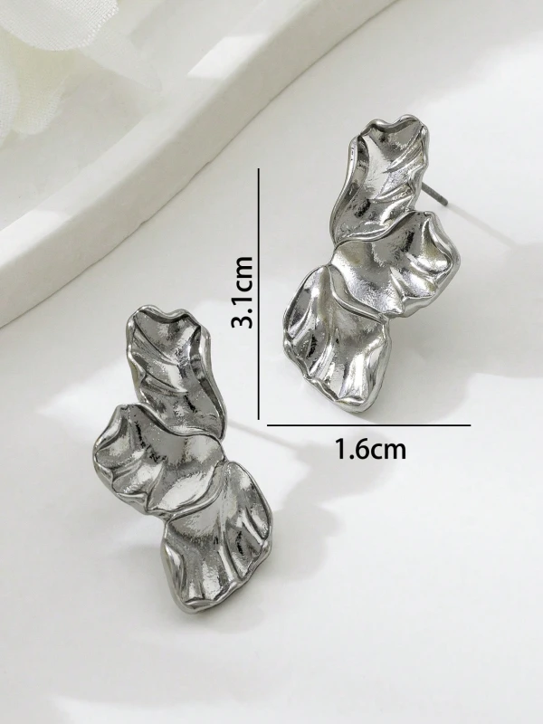 Srebrne kolczyki Silver Petals w formie trzech nieregularnych, rzeźbionych listków lub płatków, pokazane na uchu i na jasnym tle (6).webp