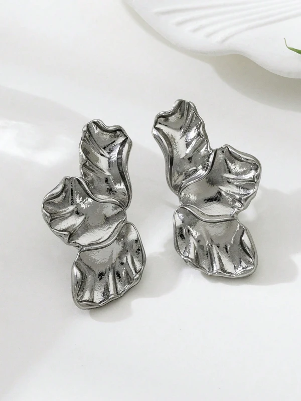 Srebrne kolczyki Silver Petals w formie trzech nieregularnych, rzeźbionych listków lub płatków, pokazane na uchu i na jasnym tle (3).webp