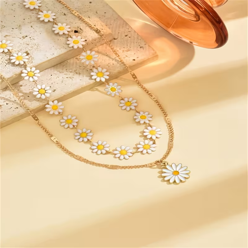 Zestaw dwóch złotych naszyjników Daisy Bloom z biało-żółtymi stokrotkami – kwiatowy choker i dłuższy naszyjnik z zawieszką stokrotką (4).webp